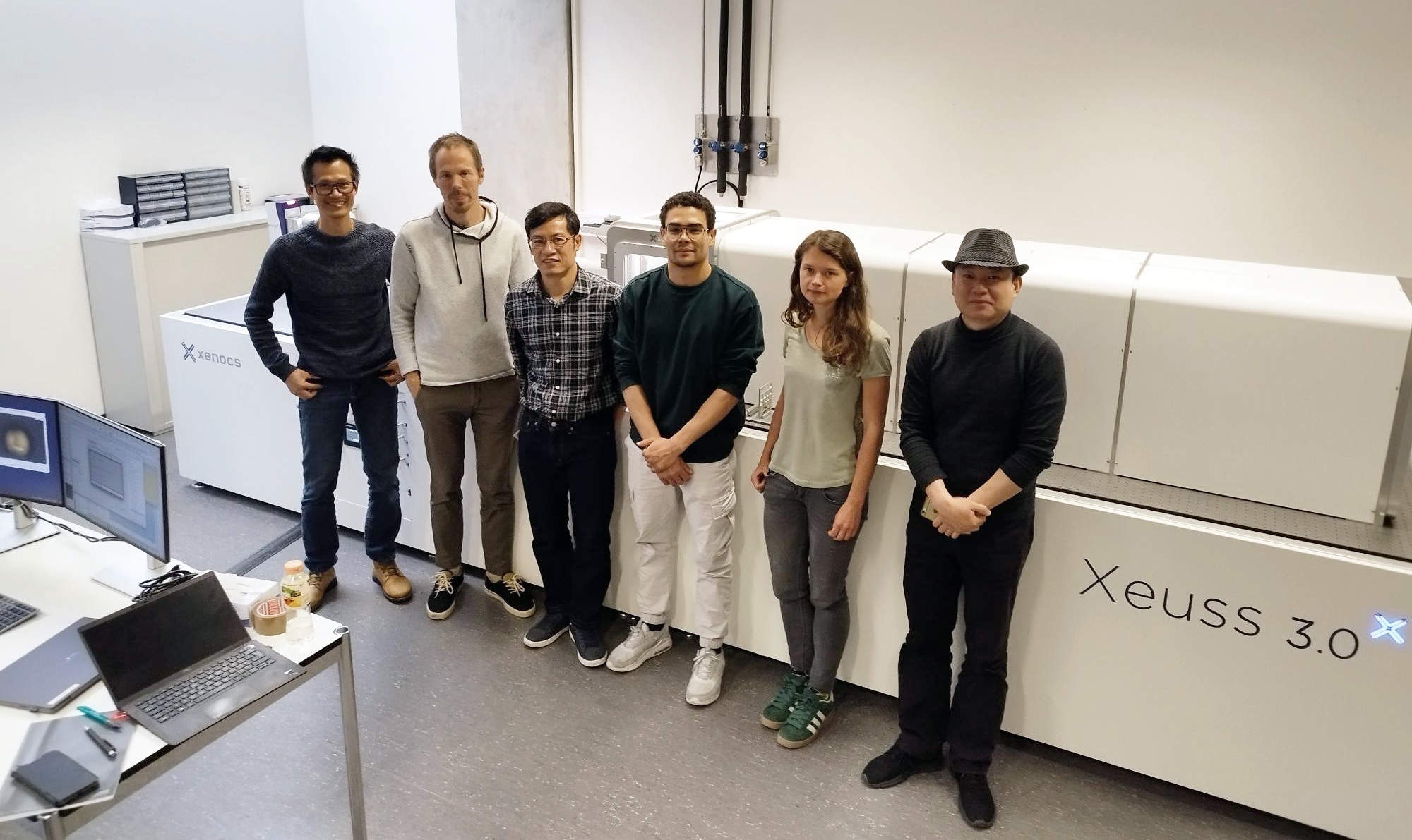 Researchers from EPFL and a Xenocs application scientist standing in front of the Xenocs Xeuss 3.0 SAXS instrument.